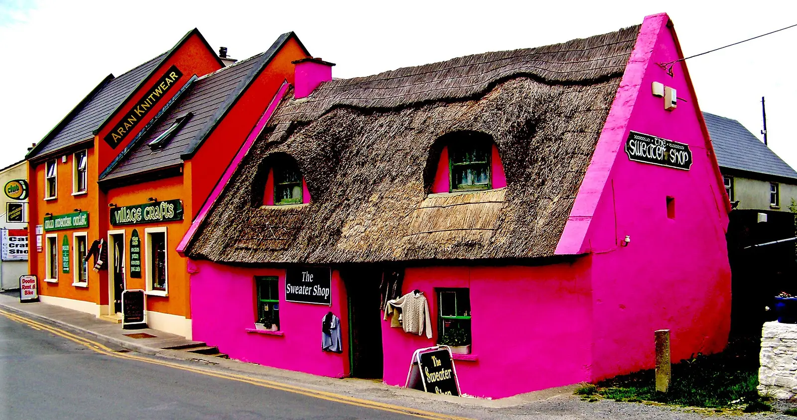 A thatched pink cottage and colourful shops on Fisher Street in Doolin