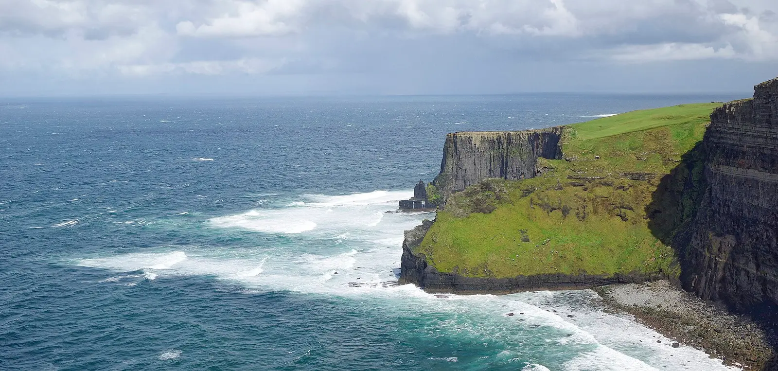 Atlantic waves breaking below the green-topped Cliffs of Moher