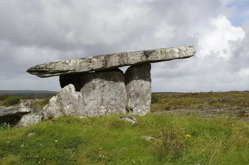 Poulnabrone portal tomb, a stone slab on two uprights, on grass in the Burren
